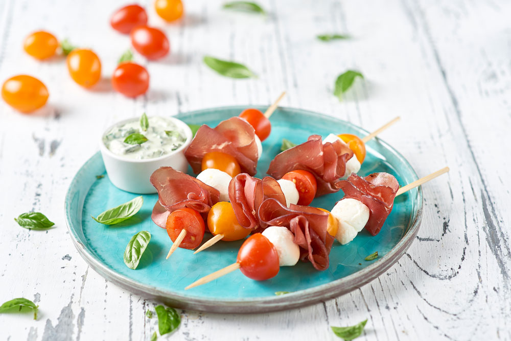 Spiedini di bresaola, mozzarelline e ciliegini bicolor con crema di basilico senza aglio e formaggio cremoso