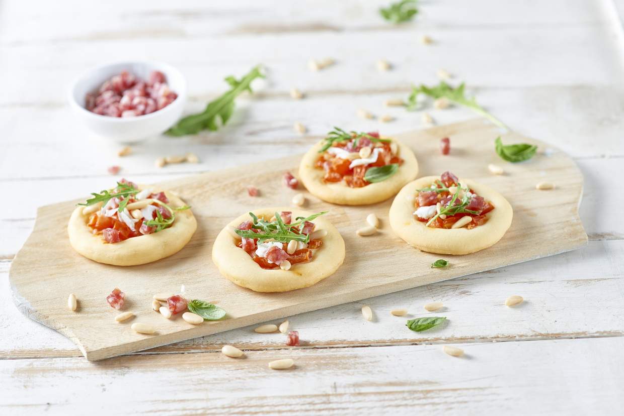 Pizzette al salame con pinoli, pomodoro fresco, burrata e rucola