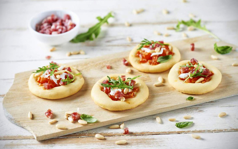 Pizzette al salame con pinoli, pomodoro fresco, burrata e rucola